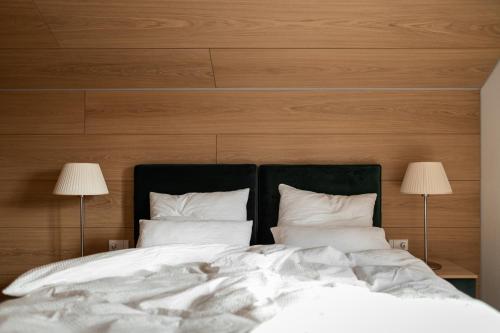 a bed with white sheets and pillows next to two lamps at Haus Engadein in Auna di Sopra