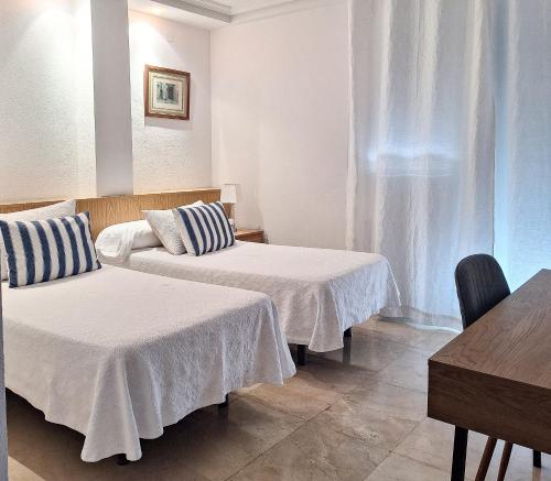 a room with two beds and a table at Hostería los Jardines in Mortera