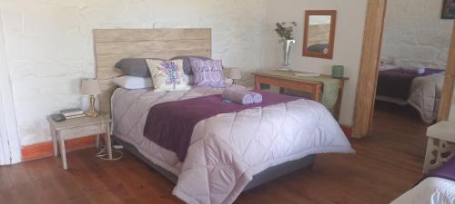 a bedroom with a large bed with purple sheets and pillows at Intaba Lodge in Elliot