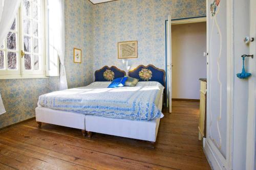 a bedroom with a bed with blue walls and wooden floors at Villa Leopoldina in Premeno