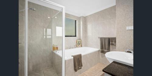 a bathroom with a shower and a tub and a sink at Executive Penthouse Apartment in Wollongong
