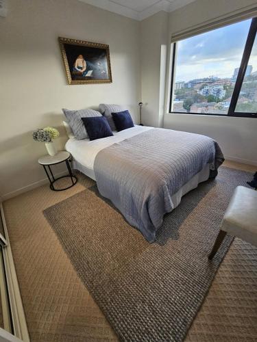 a bedroom with a large bed with a large window at Executive Penthouse Apartment in Wollongong