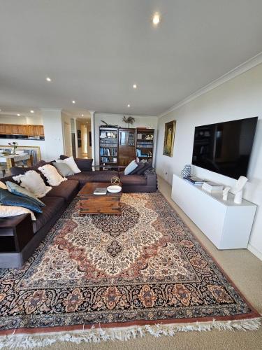a living room with a couch and a tv at Executive Penthouse Apartment in Wollongong