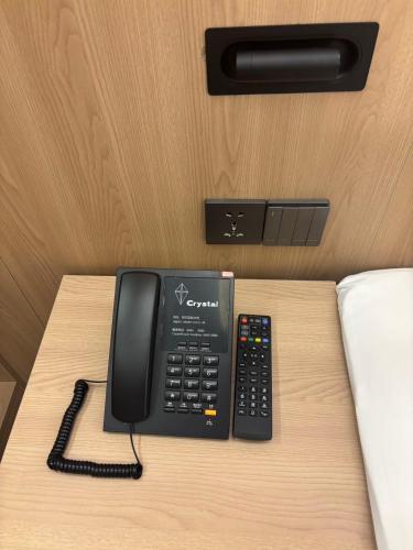 a telephone and a remote control sitting on a table at 比什凯克水晶轻奢智享酒店阿拉套广场店Bishkek Crystal Luxury Smart Hotel Ala-Too Square Branch in Bishkek
