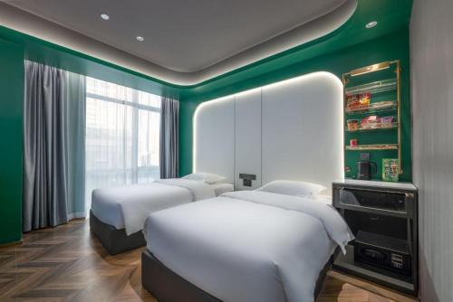 ein Zimmer mit drei Betten und einer grünen Wand in der Unterkunft Yue Tower TOP PLAY eSports Hotel Beijing Road Branch in Guangzhou