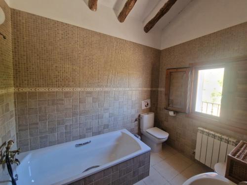 a bathroom with a tub and a toilet and a window at Villa Montesa in Elche de la Sierra