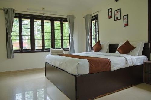 a bedroom with a large bed in a room with windows at melberry villa in Sānand