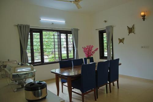 a dining room with a wooden table and blue chairs at melberry villa in Sānand