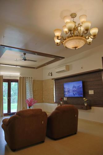 a living room with a couch and a flat screen tv at melberry villa in Sānand
