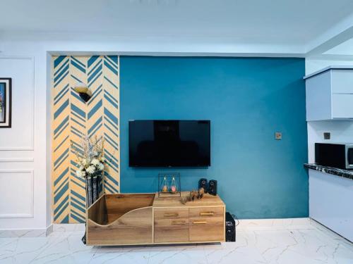 a living room with a blue wall with a tv at Bahria Breeze Apartment in Karachi