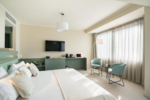 a bedroom with a large white bed and a table and chairs at Millennium Hub & Hotel in Constanţa