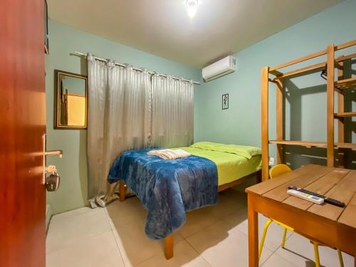 a small bedroom with a bed and a desk at Maga Inn House - Centro in Blumenau
