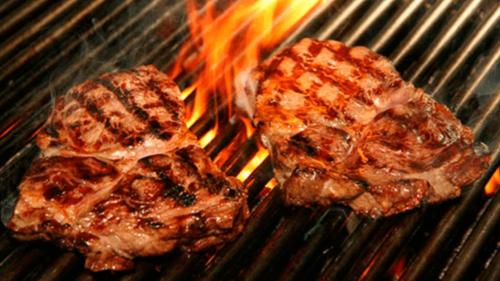 two pieces of meat are cooking on a grill at DUCASSI DELUXE playa LOS CORALES - rooftop pool and restaurants in Punta Cana