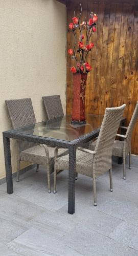 a glass table with chairs and a vase with red flowers at Guest house in Otopeni
