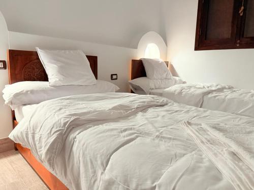 a bedroom with two beds with white sheets at Bab Al Shams Palace in Luxor