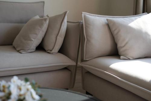 two tan couches with pillows sitting next to a table at Orikum Getaway in Orikum
