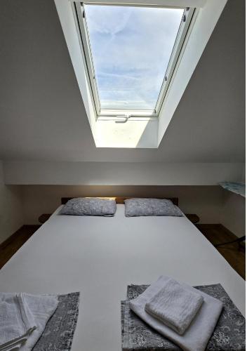 two beds in a room with a window at Apartments Sv. Jelena 2 in Pag