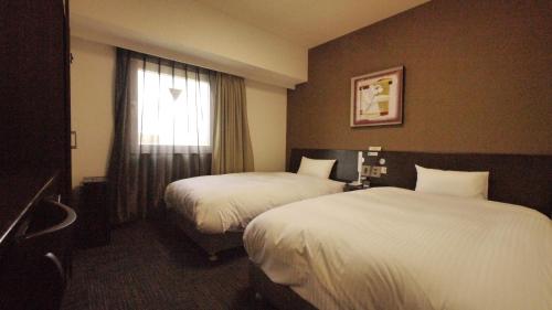 a hotel room with two beds and a window at Hotel Route-Inn Tsuruga Ekimae in Tsuruga