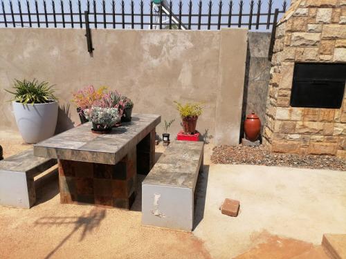 a patio with two benches and potted plants at Black Oyster in Vosloorus
