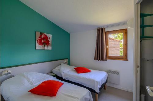 two beds in a room with green walls and red pillows at Village Vacances Passion L'Emeraude in Damvix