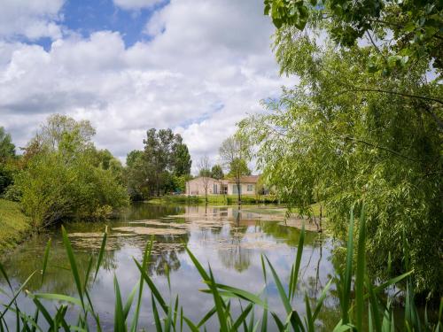 a body of water with a house in the background at Village Vacances Passion L'Emeraude in Damvix