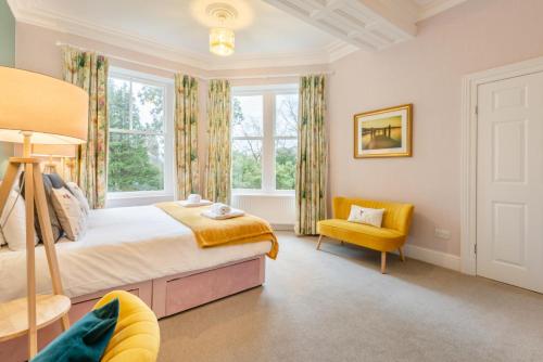 a bedroom with a large bed and a yellow chair at Redwood Rise Apartment Keswick at The Lairbeck in Keswick