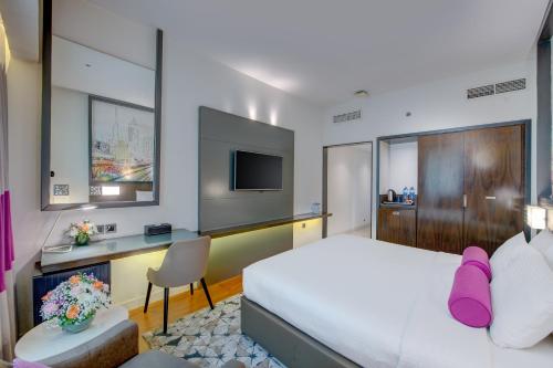 a bedroom with a bed and a desk and a tv at Howard Johnson Plaza by Wyndham Dubai Deira in Dubai