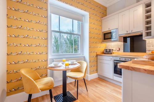 a kitchen with yellow walls and a small table and chairs at Cameron Fell Apartment Keswick at The Lairbeck in Keswick