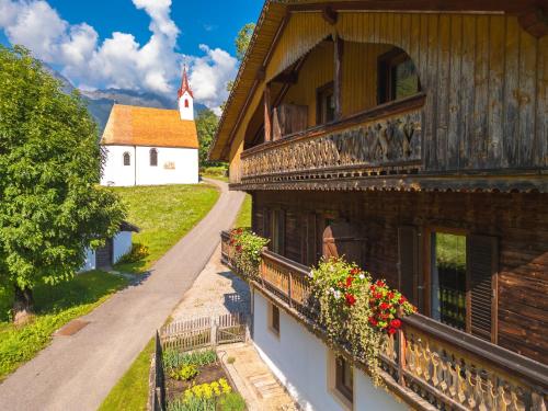 a building with flowers on a balcony and a church at Ferienhaus Oberschneider in Selva dei Molini