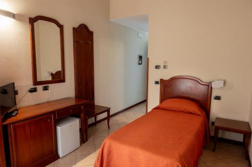 a bedroom with a bed and a dresser and a mirror at Hotel Mariuccia in Varese