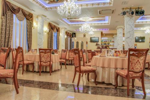 a restaurant with tables and chairs and a chandelier at Yerevan Hotel in Simferopol