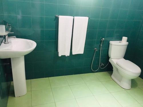 a green tiled bathroom with a toilet and a sink at Seekku Villa in Balapitiya