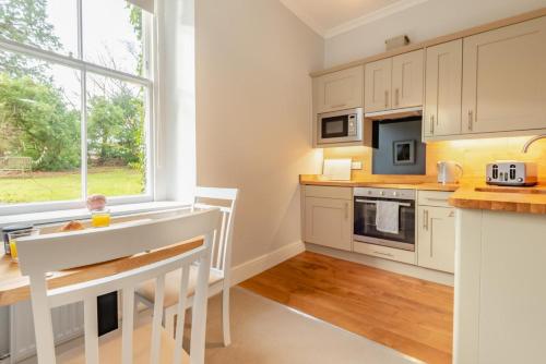 a kitchen with white cabinets and a table and a window at Bethby Beck Apartment Keswick at The Lairbeck in Keswick