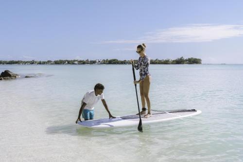 a man and a woman on a paddle board in the water at Royal Palm Beachcomber Luxury in Grand Baie