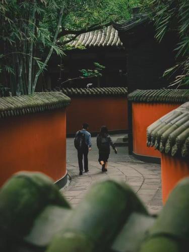 a couple of people walking down a sidewalk at BuYuan Hotel - Near Wuhou Shrine, Chunxi Road,T aikooli, Tianfu Square, People's Park, Chengdu Museum, Very close to the Sichuan University , Exit C of Huaxiba on Metro Line 1,Provides Welcome refreshments ,Minibar,Laundry & Luggage delivery service in Chengdu