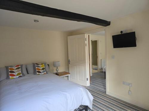 a bedroom with a white bed and a flat screen tv at Unicorn Hotel Llanidloes in Llanidloes