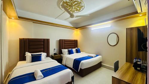 a hotel room with two beds and a mirror at Hotel Blue Sky Dhaka Mirpur in Dhaka