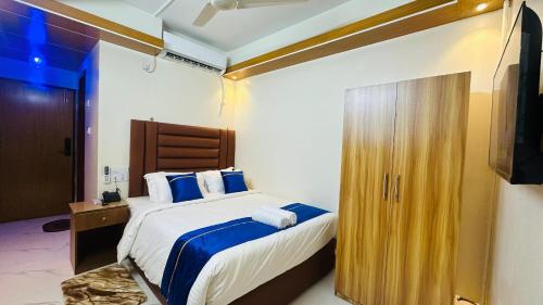 a bedroom with a bed with blue sheets and a television at Hotel Blue Sky Dhaka Mirpur in Dhaka