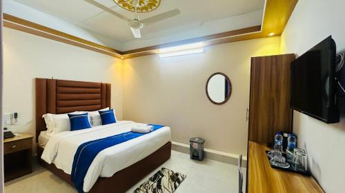 a bedroom with a bed with blue pillows and a tv at Hotel Blue Sky Dhaka Mirpur in Dhaka