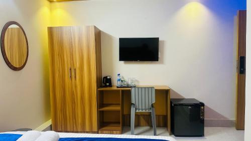 a bedroom with a desk with a television on a wall at Hotel Blue Sky Dhaka Mirpur in Dhaka