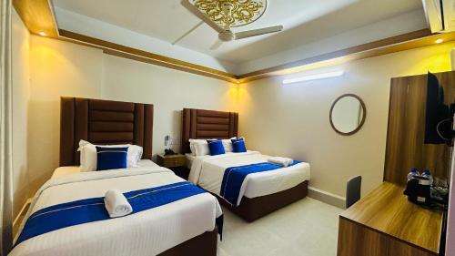 a hotel room with two beds and a mirror at Hotel Blue Sky Dhaka Mirpur in Dhaka