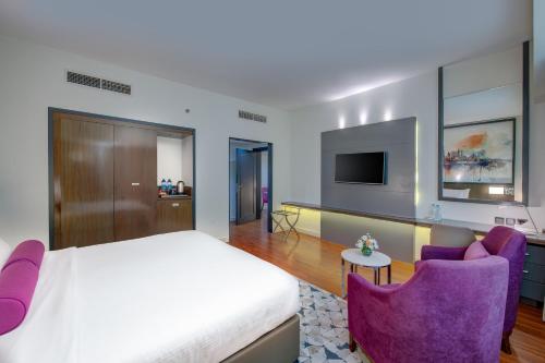 a bedroom with a bed and two purple chairs at Howard Johnson Plaza by Wyndham Dubai Deira in Dubai