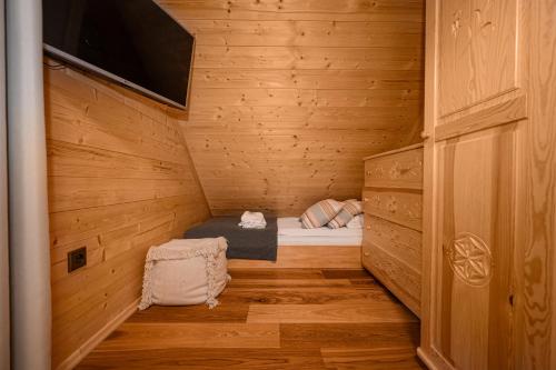 a small room with a bed in a wooden cabin at Domek drewniany w górach Jacuzzi & Balia - Osada Chełm in Stróża