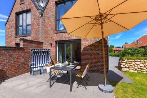 a patio with a table and an umbrella at Ferienhaus Fischerstuuv in Carolinensiel