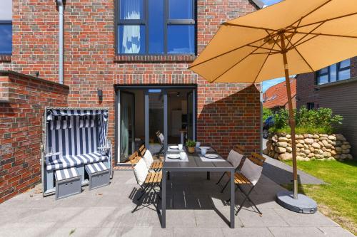 a patio with a table and an umbrella at Ferienhaus Fischerstuuv in Carolinensiel