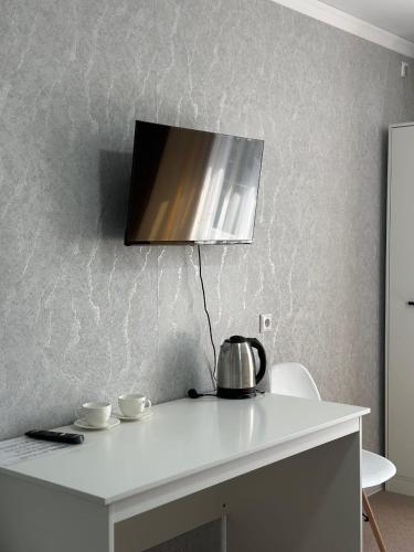 a tv on the wall above a white table at Уютные номера для семейных пар in Uralsk