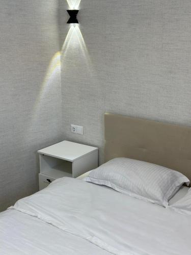 a bedroom with a white bed with a light above it at Уютные номера для семейных пар in Uralsk