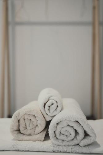 a pile of towels sitting on top of a bed at Ξενώνας OLEAVIA in Kalamata