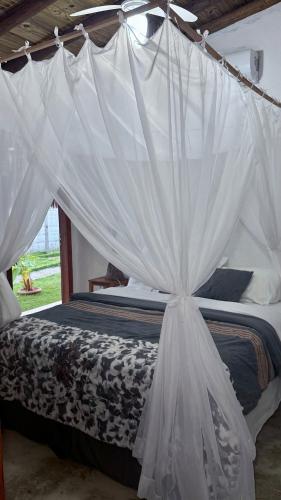 a bed with white mosquito netting in a room at Suítes Independentes em Trancoso in Trancoso