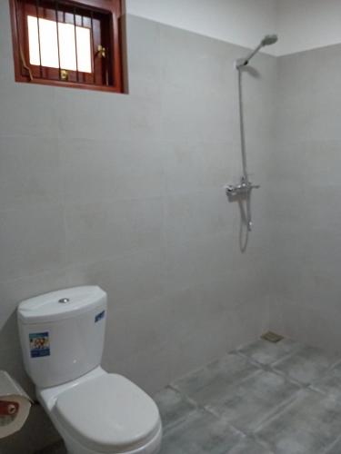a bathroom with a white toilet and a window at Twins Beach Villa in Moragalla